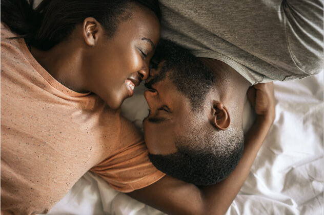 A woman and man lying in bed with her arm around him